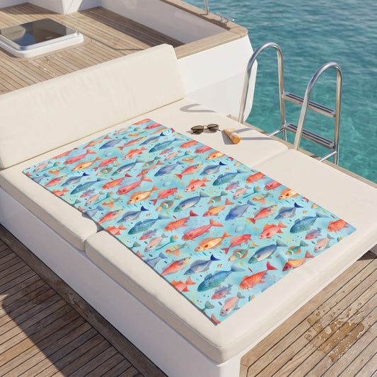 Happy Swimming Fish beach towel, displayed in a summer setting.