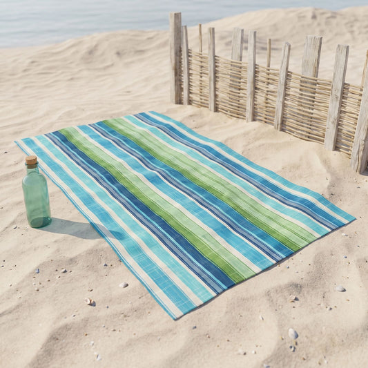 Ocean Whisper Stripes beach towel, displayed in a summer setting.