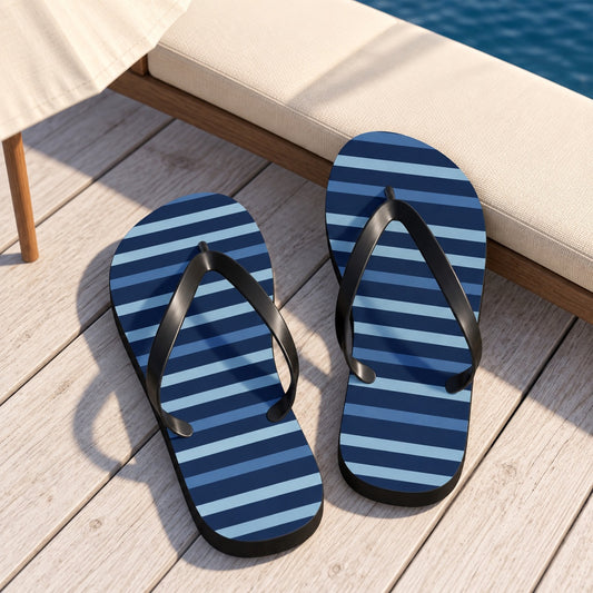 Shades of Dark Blue Stripes Flip Flops. Lifestyle scene: Navy-striped pool parasol lounge; dry whitewashed deck, cream chaise, deep blue water beyond