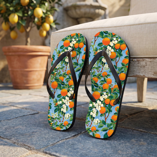 Citrus Blue Bliss Flip Flops. Lifestyle scene: Citrus courtyard fountain terrace; dry blue-grey stone, lemon pot at distance, cream linen chair