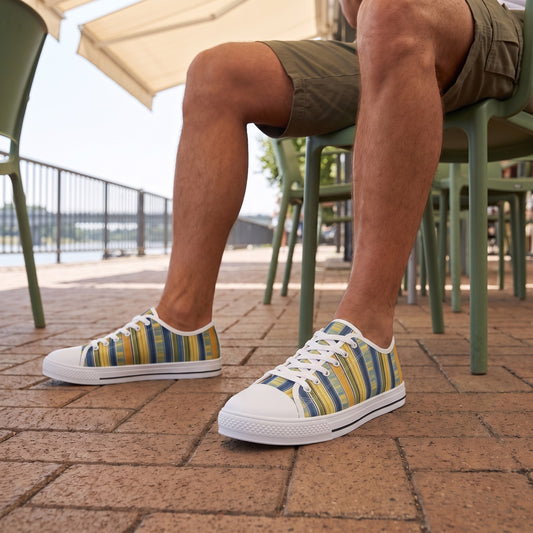 Summer Stripes Delight Men's Low Top Sneakers — An outdoor riverside café terrace on a clear summer afternoon, a close low-angle view of a man taking a break after strolling.