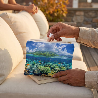 Small Coral Reef Dreamscape accessory pouch (8.35 × 5.98 inches) in use: man in a flax shirt lifts a lip balm from his pouch resting against a closed novel. Lifestyle mockup with hands showing scale.