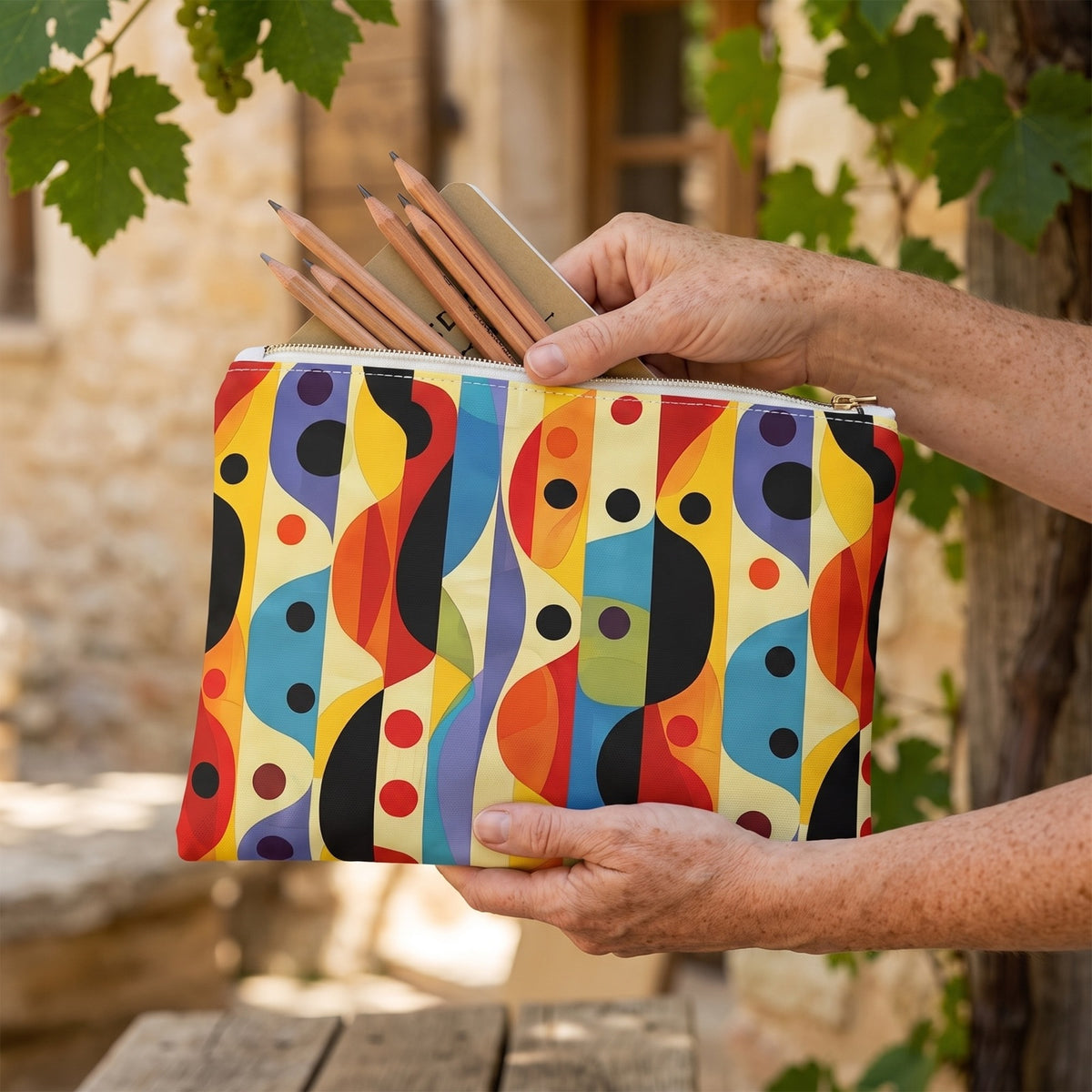 Large Linear Color Mesa accessory pouch (11.81 × 8.35 inches) in use: woman gathers drawing pencils and a slim field journal in pouch. Lifestyle mockup with hands showing scale.