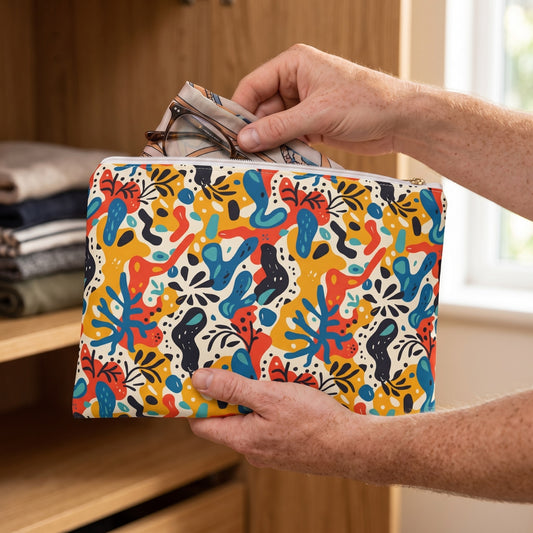 Large Spice of Life accessory pouch (11.81 × 8.35 inches) in use: man places a folded thin travel scarf and glasses into pouch supported on one forearm. Lifestyle mockup with hands showing scale.