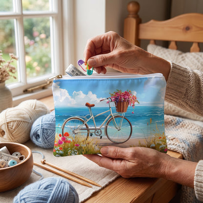 Small Daisy Beach Rider accessory pouch (8.35 × 5.98 inches) in use: older woman collects stitch markers and a small measuring tape into pouch beside wool. Lifestyle mockup with hands showing scale.