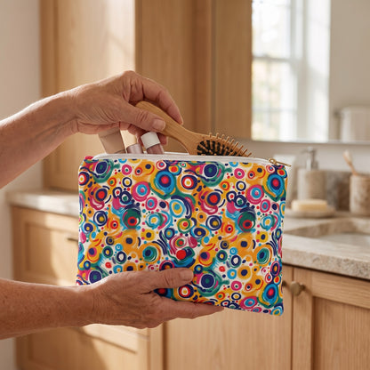 Large Pop Art Swirls accessory pouch (11.81 × 8.35 inches) in use: woman organizes a hairbrush and a few small cosmetic tubes inside pouch. Lifestyle mockup with hands showing scale.