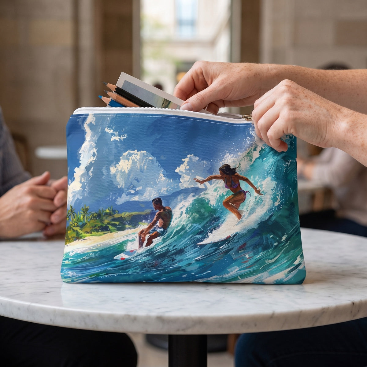 Large Wave Rider accessory pouch (11.81 × 8.35 inches) in use: woman packs sketch pencils and a slim postcard folio into pouch. Lifestyle mockup with hands showing scale.