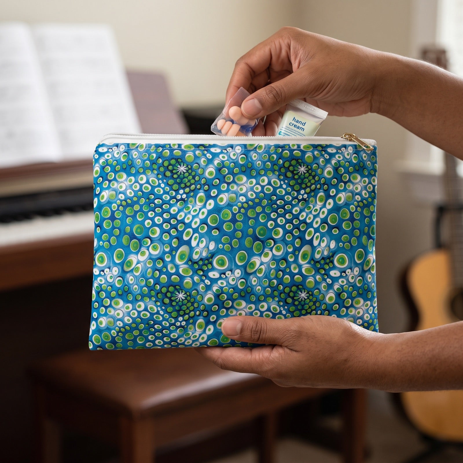 Small Embryonic Space Pods accessory pouch (8.35 × 5.98 inches) in use: pianist places earplugs and a tiny hand-cream tube in pouch, keys softly out of focus. Lifestyle mockup with hands showing scale.