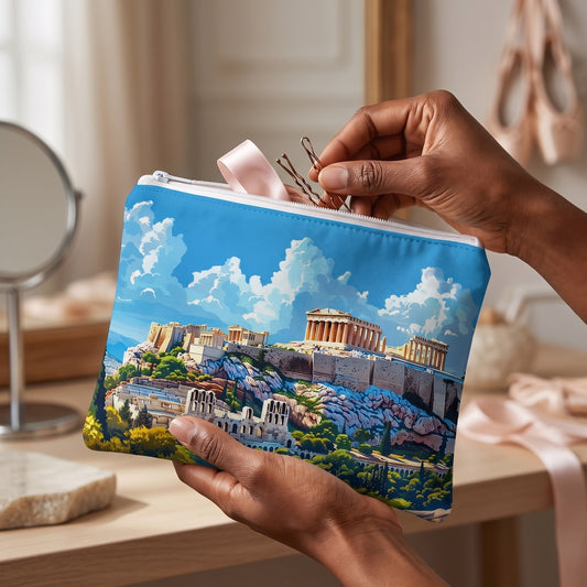 Small Acropolis Skyline Splendor accessory pouch (8.35 × 5.98 inches) in use: dancer in a soft gray wrap packs hairpins and a folded hair ribbon into pouch supported by one hand. Lifestyle mockup with hands showing scale.