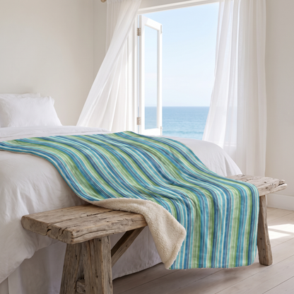 Ocean Whisper Stripes sherpa fleece blanket on a driftwood bench in a beach-house bedroom