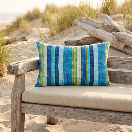 Ocean Whisper Stripes lumbar outdoor pillow styled in a sunlit outdoor setting